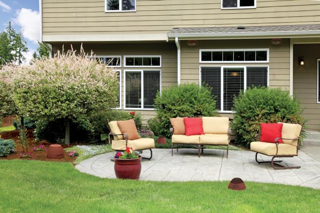 A backyard patio with furniture and a landscaped garden