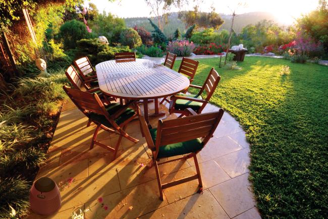 A backyard patio table with sun shining on it during golden hour